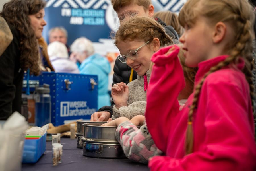 Two young children look at the archaeological artefacts with interest at our stall.