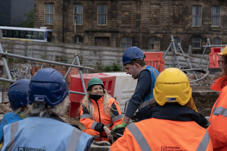 A group of archaeologists and members of the public discuss Sheffield Castle excavation.