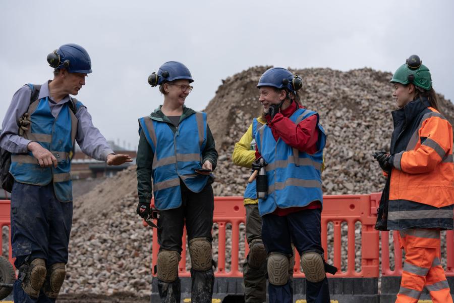 Members of the public walk through Sheffield Castle excavation tours in a blue high-vis jacket.