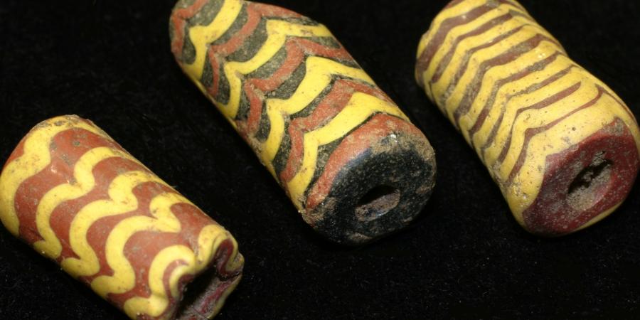 three Anglo-Saxon coloured glass beads in yellow, red and black with line decoration 