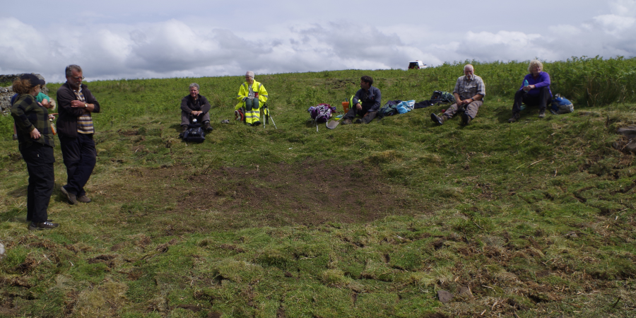 Volunteers sit near re-turfed trench at Yatesfield