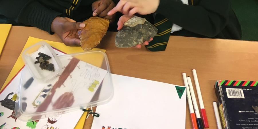 Pupils from St James' C of E Primary School studying a palaeolithic handaxe and a replica