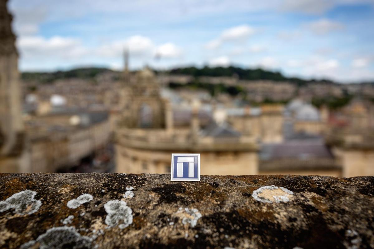 Wessex Archaeology logo badge photographed on abbey balcony overlooking Bath cityscape 