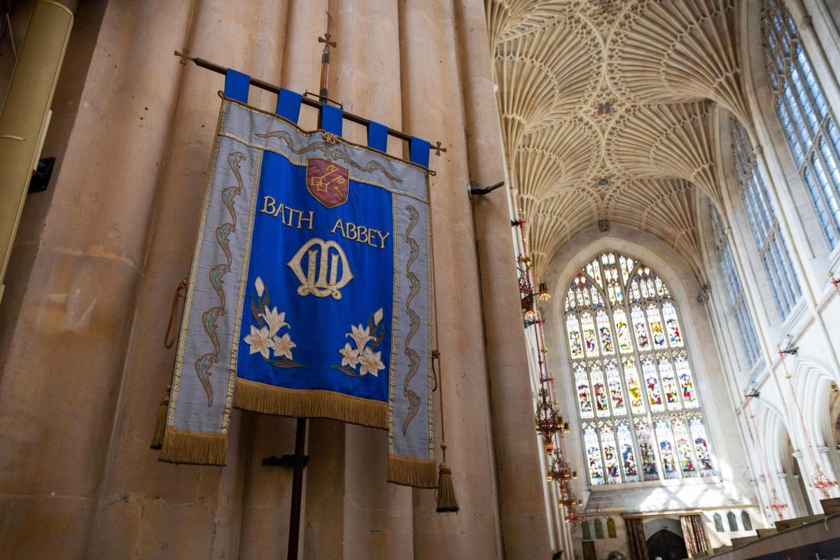 Fabric banner hoisted onto wall within Bath Abbey