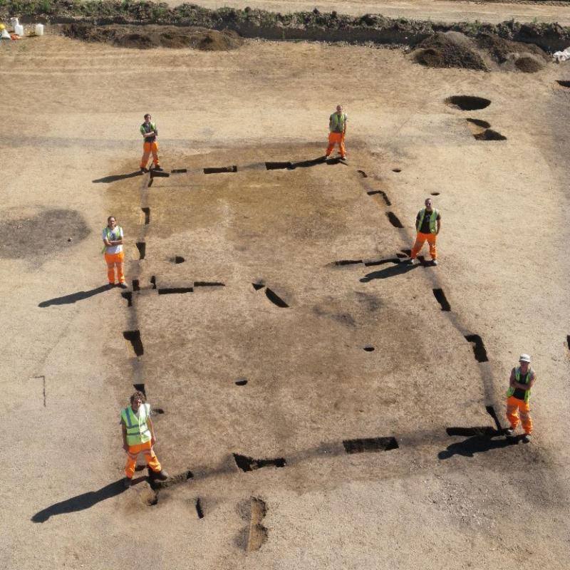 archaeologists standing by the 6 postholes around the foundation ditch of the house