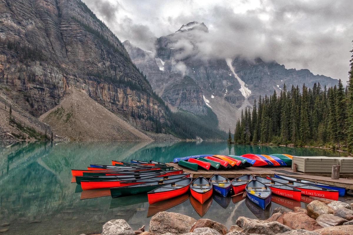 Photograph of canoes on a lake surrounded by mountains, taken by Tom Westhead during his time in Canada