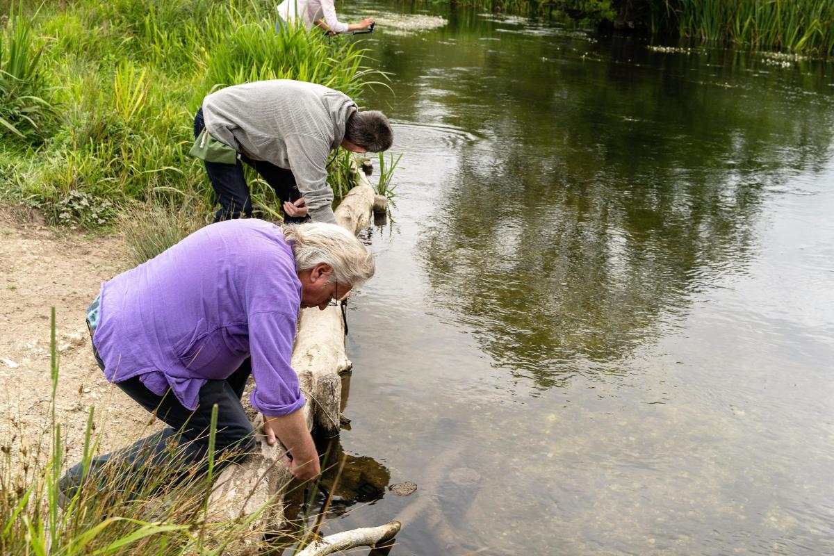 Three participants in The Ripple Effect project interact with the River Avon from the bank