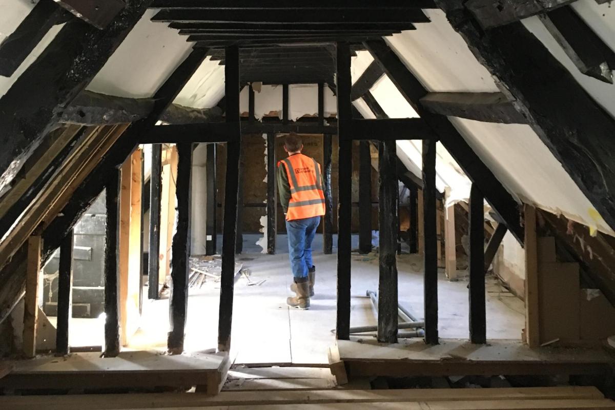 The interior of the Packhorse Inn, showing an archaeologist standing amid roof beams